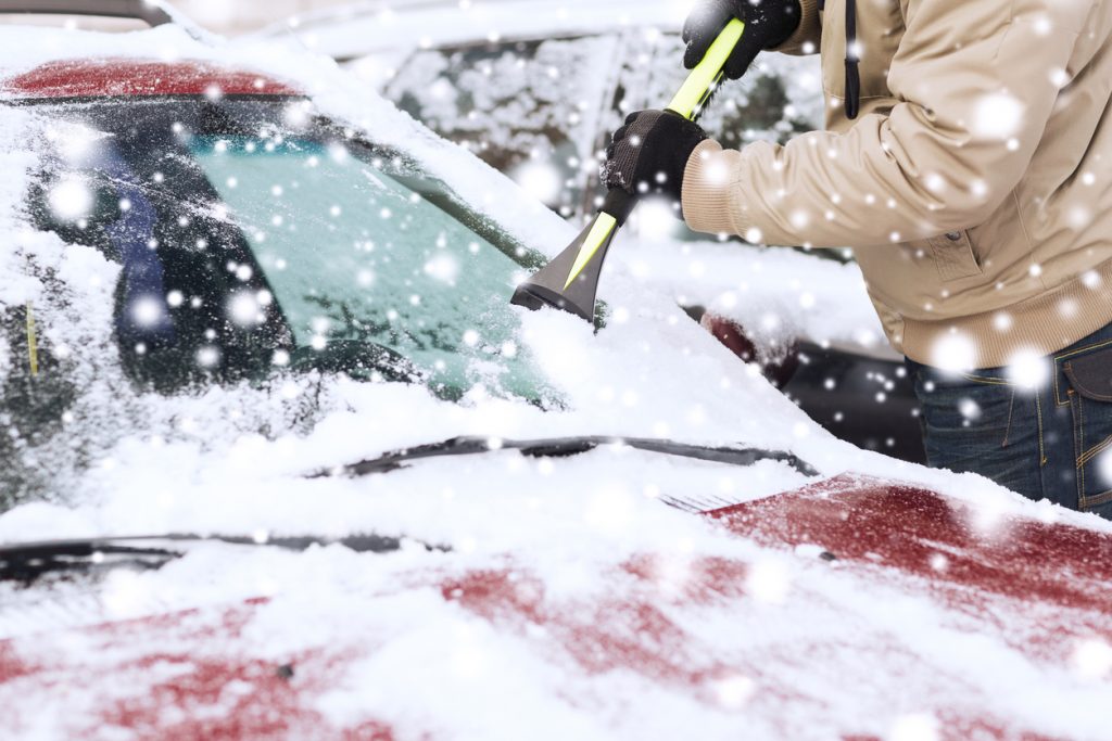 Scraping snow off windshield in the winter