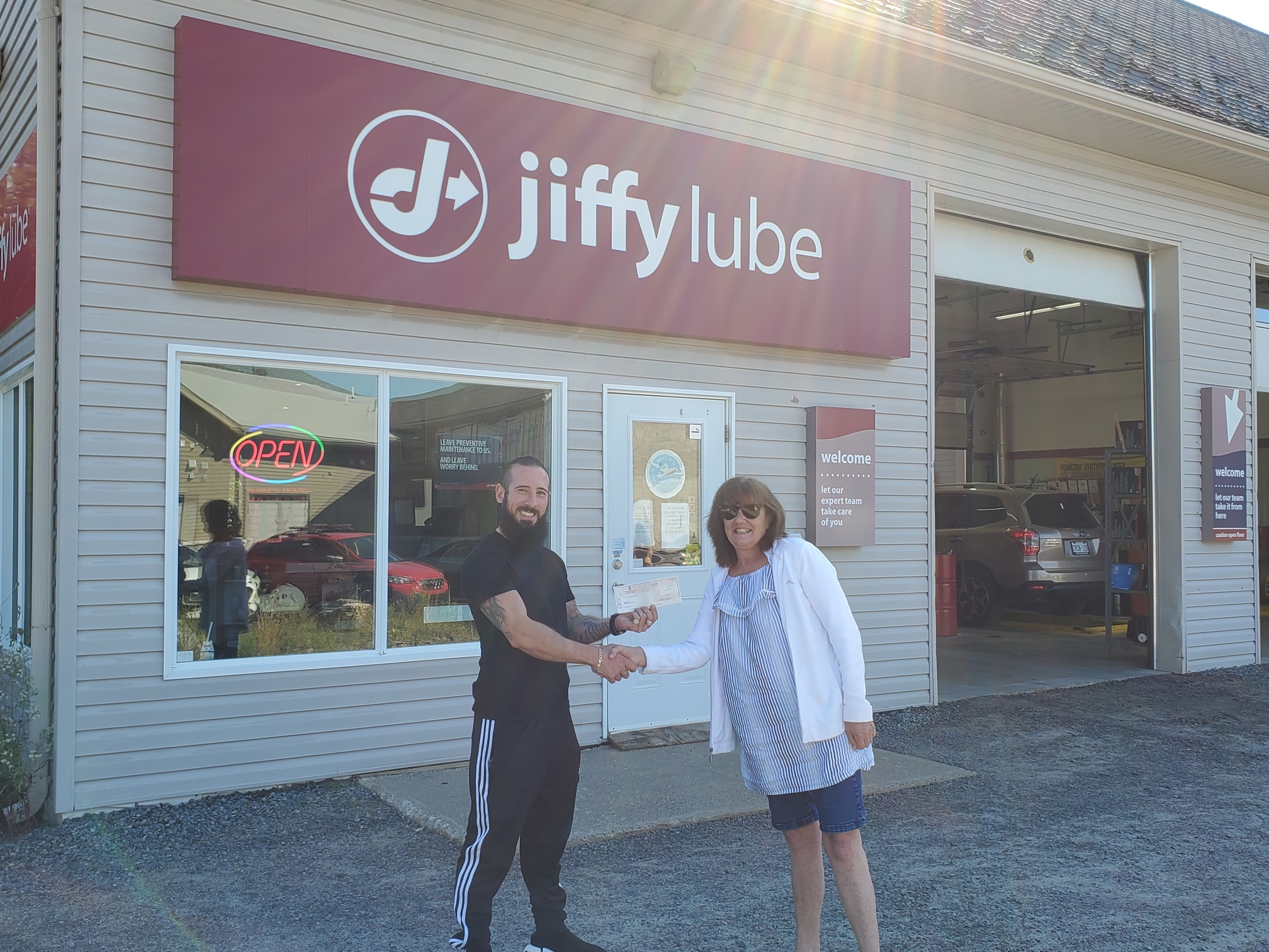 Winner from Jiffy Lube's 20th Anniversary Contest receiving her prize in front of a Jiffy location
